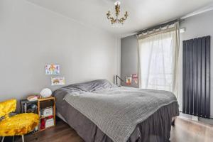 1 dormitorio con 1 cama, 1 silla y 1 ventana en Maison duplex avec jardin, en Saint-Ouen