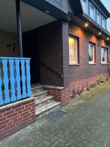 een stenen huis met een blauwe leuning en een trap bij Ferienwohnung am Moor in Rehden