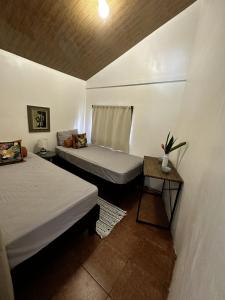 Habitación pequeña con 2 camas y mesa. en Casa Morpho Uvita Guesthouse, en Uvita