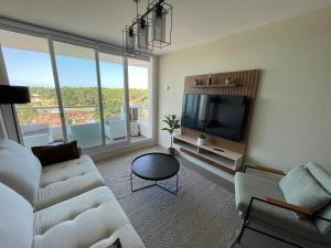 ein Wohnzimmer mit einem Sofa und einem Flachbild-TV in der Unterkunft Punta del Este - Green Life - Top amenities in Punta del Este