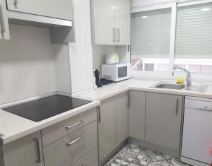 eine weiße Küche mit einer Spüle und einer Mikrowelle in der Unterkunft PRIMERA LINEA DE PLAYA-CULLERA in Cullera
