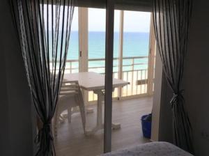 a room with a table and a balcony with the ocean at PRIMERA LINEA DE PLAYA-CULLERA in Cullera