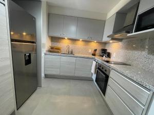 una cocina con armarios blancos y electrodomésticos de acero inoxidable en Punta del Este - Green Life - Top amenities en Punta del Este