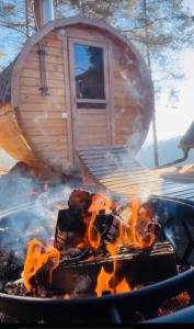 un feu dans un grill avec une maison en arrière-plan dans l'établissement Romantic cabin with hot/cold tub and finnish sauna, à Šentvid pri Stični