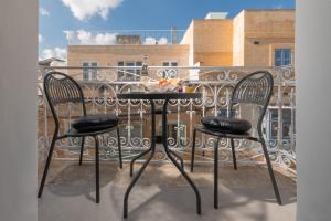 a table with two chairs on a balcony at Encanto Townhouse Sliema in Sliema