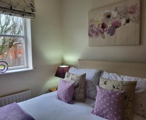a bedroom with a bed with purple pillows and a window at Grayz Townhouse - Free onsite parking for 2 cars in Lincoln