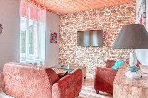 a living room with a couch and a tv on a stone wall at Villa Orkagna in Perros-Guirec