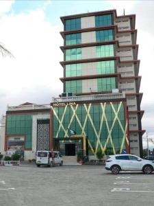 a large building with cars parked in a parking lot at Hôtel Lina in Bordj Bou Arreridj