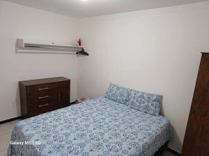 a bedroom with a bed and a dresser with a blue blanket at Apartamento 2 quartos na área central perto do GV Shopping in Governador Valadares