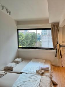 Duas camas num quarto com uma janela grande em Room 580m bts Prompong em Klong Toi