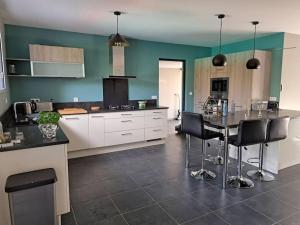 a kitchen with white cabinets and a table with black chairs at UN COIN DE PARADIS in Lit-et-Mixe