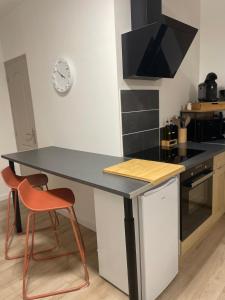 a kitchen with a black counter top and two orange chairs at - Le Gambetta - in Moulins