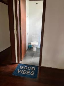 a bathroom with a toilet and a blue welcome mat at Casa próxima ao mar, Camburi. in São Sebastião