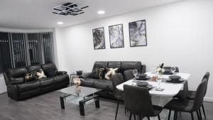 a living room with a black couch and a table at 3-Bedroom Semi near Etihad Football Stadium, Tourist attractions, Manchester City Centre and Transport Links - Sky n Netflix in Manchester