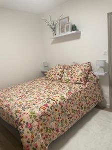 - un lit avec une couette à fleurs dans une chambre dans l'établissement - Le Gambetta -, à Moulins