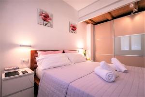 1 dormitorio con 1 cama grande con sábanas y almohadas blancas en Casa Mia ,APT WiFi e Parcheggio nel cuore del Friuli, en Osoppo