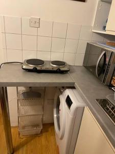 a kitchen counter with a stove and a washing machine at Private, homely, 1 bedroom apartment SW London. in Hanworth