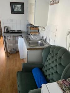 a kitchen with a green couch and a sink at Private, homely, 1 bedroom apartment SW London. in Hanworth