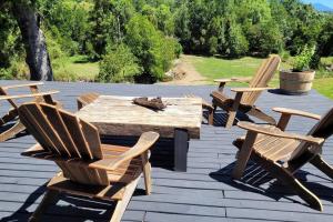 un grupo de sillas y una mesa de madera en una terraza en Casa de campo sobre el rio, en llifen