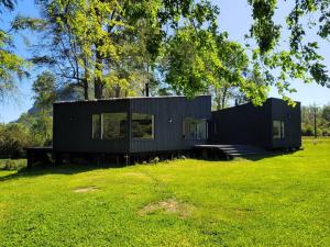 ein schwarzes Haus auf einem üppigen grünen Feld in der Unterkunft Casa de campo sobre el rio in llifen