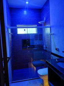 La salle de bains bleue est pourvue de toilettes et d'un lavabo. dans l'établissement Suíte Alto Padrão, à Uberaba