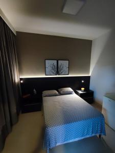 a bedroom with a bed and two pictures on the wall at Suíte Alto Padrão in Uberaba