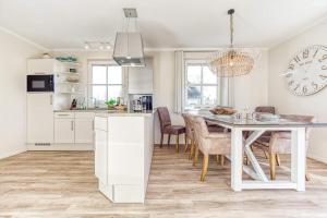 a kitchen and dining room with a white table and chairs at Ferienhaus Haubenlerche 27 in Fuhlendorf