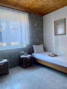 Habitación con cama y ventana con 2 mesas en Panoramic View Guest House, en Gjirokastra