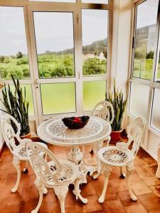 een tafel en stoelen in een kamer met ramen bij Casa Margarita in Cudillero