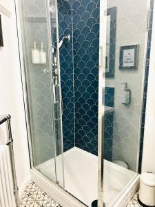 a bathroom with a shower with blue and white tiles at Nine Cooper Lane, Holmfirth in Holmfirth