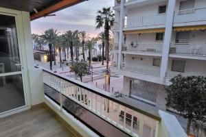 a balcony with a view of a street and palm trees at Apartamento primera línea de mar - cerca de Portaventura in Salou