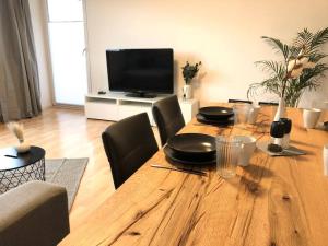 een houten tafel met stoelen en een televisie in de woonkamer bij LIME HOMES: Küche, Balkon, Netflix in Hildesheim