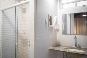 W białej łazience znajduje się umywalka i lustro. w obiekcie Porteño Loft Búzios w mieście Búzios