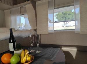 提比里亞的住宿－טבע של קרוואן，一间设有一张桌子的房间,配有两杯葡萄酒和水果