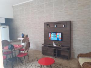 een woonkamer met een tv en een tafel en stoelen bij Casa com boas acomodações in Itanhaém