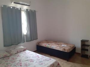 een slaapkamer met twee bedden en een raam bij Casa com boas acomodações in Itanhaém