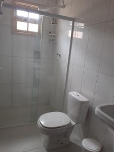 een witte badkamer met een toilet en een wastafel bij Casa com boas acomodações in Itanhaém +5 foto's