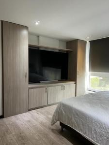 a bedroom with a bed and a large flat screen tv at Retirada in Rionegro