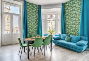 a living room with a blue couch and a table and chairs at Downtown Delight - Erzsébet BLVD - 13 PPL in Budapest +42 photos