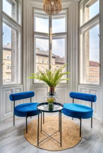 a table with blue chairs in a room with windows at Downtown Delight - Erzsébet BLVD - 13 PPL in Budapest