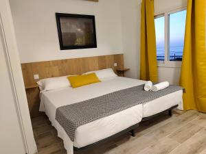 1 dormitorio con 1 cama grande y cortinas amarillas en Hierro, en La Frontera