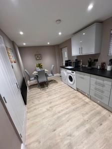 a kitchen with white cabinets and a table with chairs at Premier inn comfort mattresses - sleeps 6 in Middleton