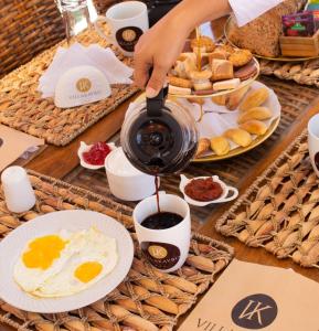 una persona vertiendo café en una mesa con alimentos para el desayuno en Apart-hotel Villakayro, en Moquegua