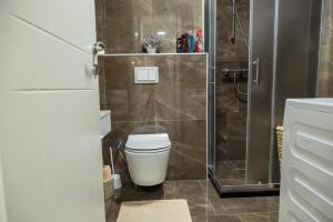 a bathroom with a toilet and a glass shower at White Apartment Prishtina in Pristina +13 photos