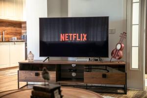 a flat screen tv on a wooden entertainment center at White Apartment Prishtina in Pristina