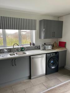 a kitchen with a sink and a washing machine at Apple Barn Guest House in Wisbech