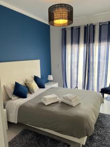 a bedroom with a large bed with blue walls at Apartamento Palomar in Pombal