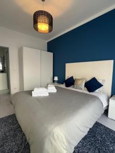 a bedroom with a large bed with blue walls at Apartamento Palomar in Pombal