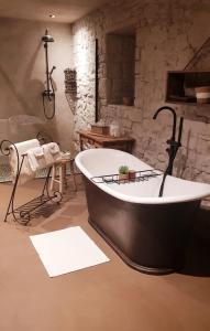 bañera en una habitación con pared de piedra en Le Lodge des Flâneurs, en Vielsalm