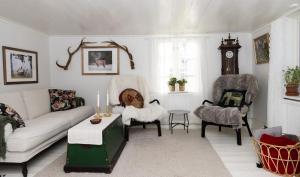 a living room with a couch and chairs and a clock at Grandma's cottage in Tanum